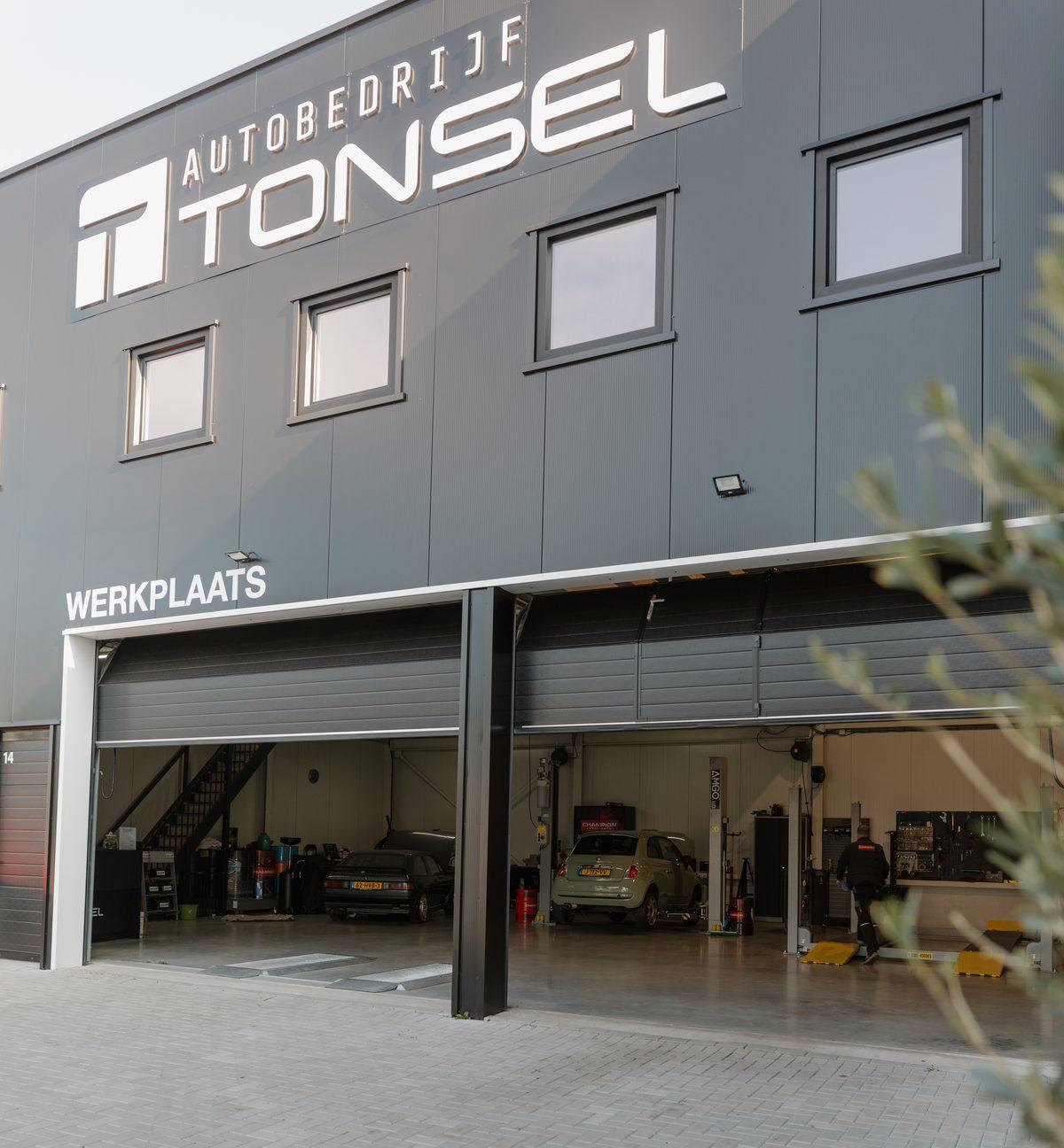Het pand van Autobedrijf Tonsel met twee open werkplaatsdeuren