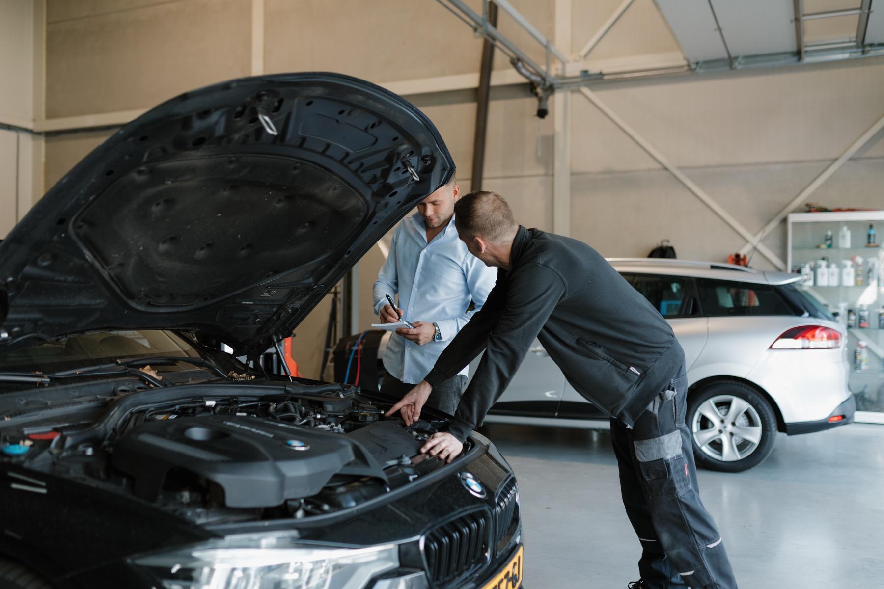 Monteur en adviseur van Autobedrijf Tonsel bekijken samen de motor van een BMW